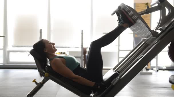 Bonito ajuste menina fazendo exercícios no simulador — Vídeo de Stock