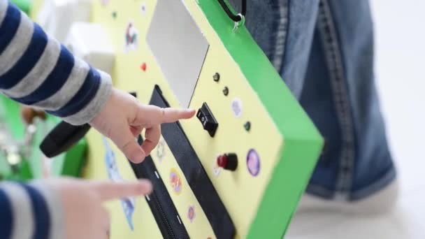 Little baby boy intently playing with busy board — Stock Video