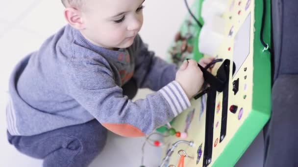 Little baby boy intently playing with busy board — Stock Video