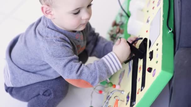 Liten pojke uppmärksamt spelar med upptagen styrelse — Stockvideo