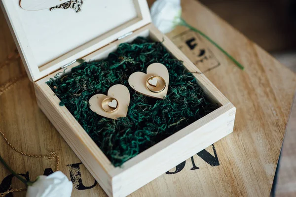Два золоті обручки в декоративній дерев'яній коробці на зеленому листі — стокове фото