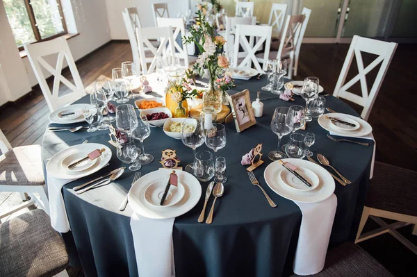 Vasos, flores, tenedor, cuchillo servido para la cena en restaurante con interior acogedor , — Foto de Stock
