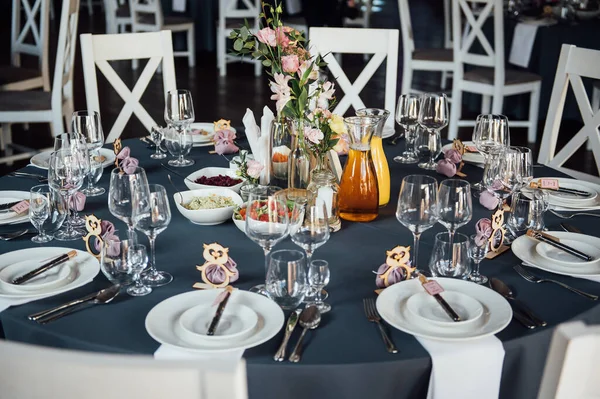 Vasos, flores, tenedor, cuchillo servido para la cena en restaurante con interior acogedor , — Foto de Stock