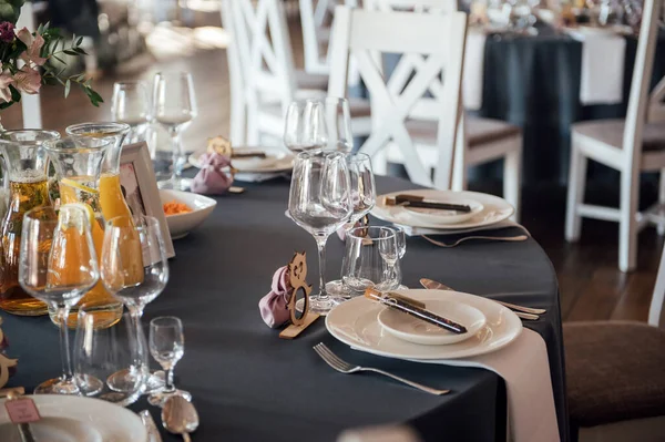 Vasos, flores, tenedor, cuchillo servido para la cena en restaurante con interior acogedor , — Foto de Stock