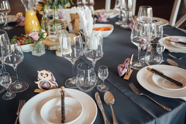 Glasögon, blommor, gaffel, kniv serveras till middag i restaurang med mysig inredning, — Stockfoto