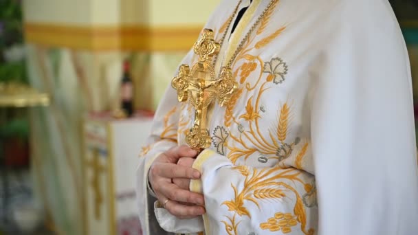 Den ortodoxa prästen står i kyrkan och håller ett kors i sina händer — Stockvideo