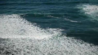 Beyaz köpüklü dalgalar Tenerife 'de siyah volkanik kumla kumları kırıyor..