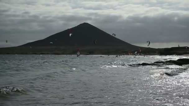 Wiele kolorowych latawców na plaży i kitesurfingu jazdy fale podczas wietrznego dnia — Wideo stockowe