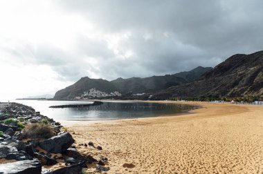 Altın kumun, palmiye ağaçlarının, güneş panjurlarının tepesinden bak. bulutlu hava