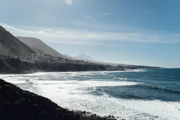 Weiße schäumende Wellen am Strand mit schwarzem Vulkansand auf Teneriffa. — Stockfoto