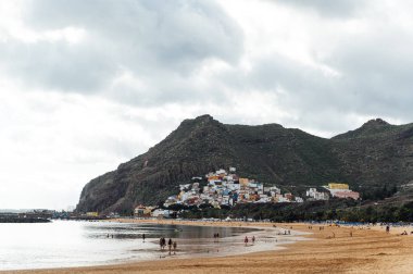 Altın kumun, palmiye ağaçlarının, güneş panjurlarının tepesinden bak. bulutlu hava