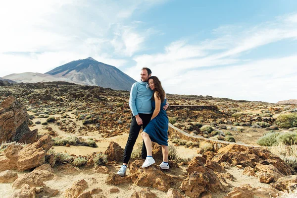 Beau jeune couple d'amoureux posant sur un champ rocheux sur un fond de volcan — Photo