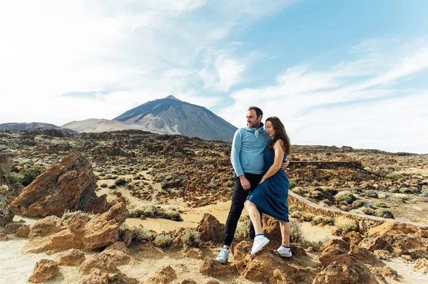 Bela jovem casal de amantes posando em um campo rochoso em um fundo de um vulcão — Fotografia de Stock