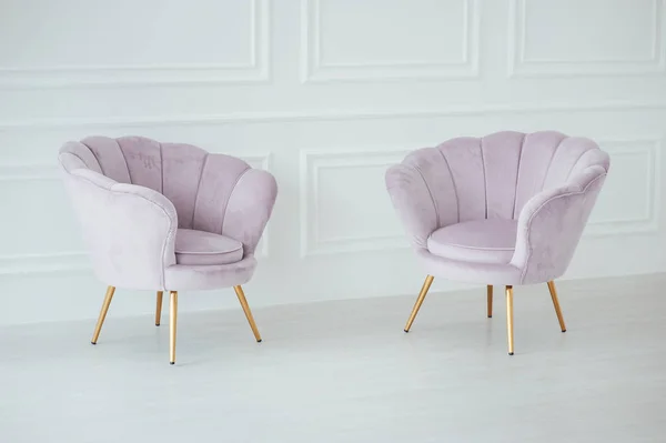 beautiful and comfortable pink armchairs stand in a spacious room near the wall.