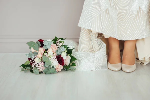 Wedding shoes of the bride with a bouquet of peonies and other flowers. — Stockfoto