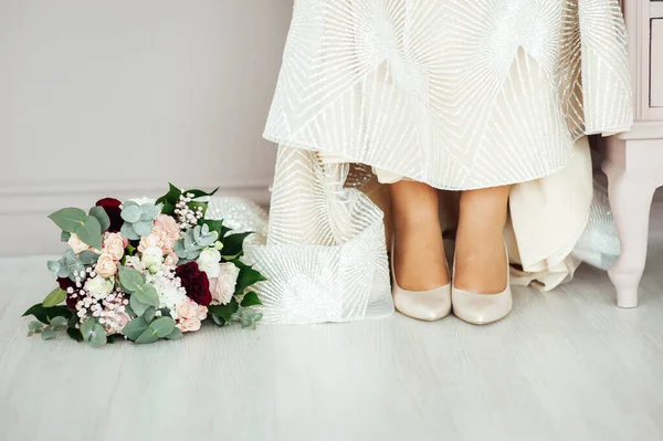 Wedding shoes of the bride with a bouquet of peonies and other flowers. — Stockfoto