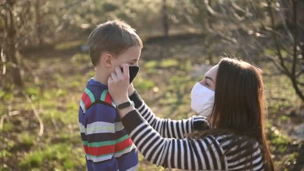 Şefkatli anne, oğlunu virüslere karşı korumak için maske takıyor. — Stok video
