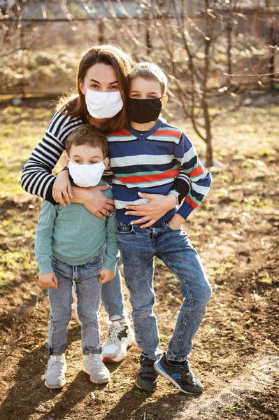 A loving mother holds and hugs her children. They wear protective masks against the virus. — Stock Photo, Image