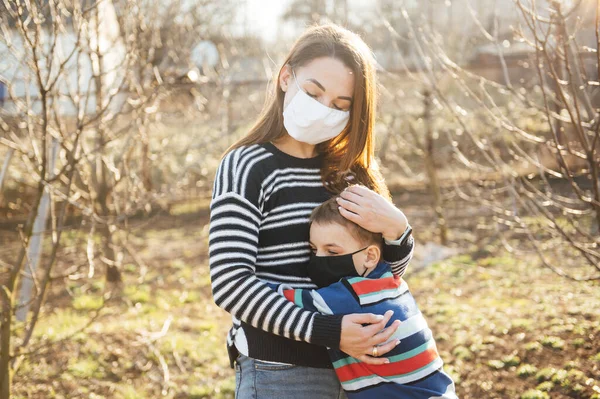 Şefkatli anne, maskeli çocuğu virüsten korumak için kucaklıyor.
