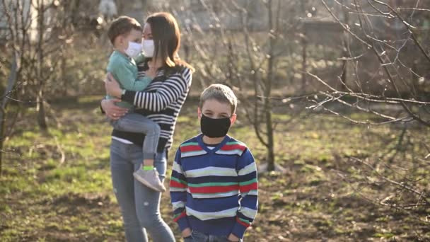 Vårdande mor kramar det maskerade barnet, och det andra barnet är framför — Stockvideo