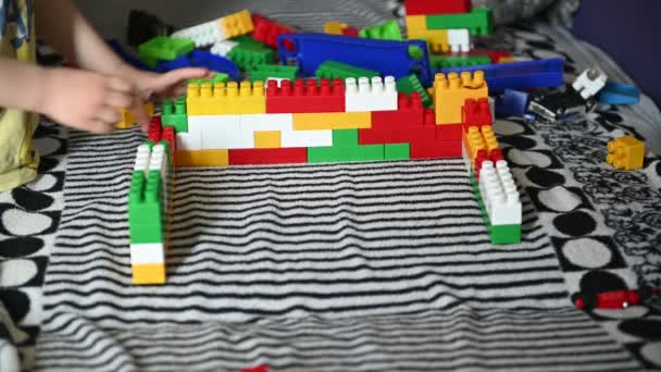 Happy child playing in the colored blocks on a striped sofa — Stock Video