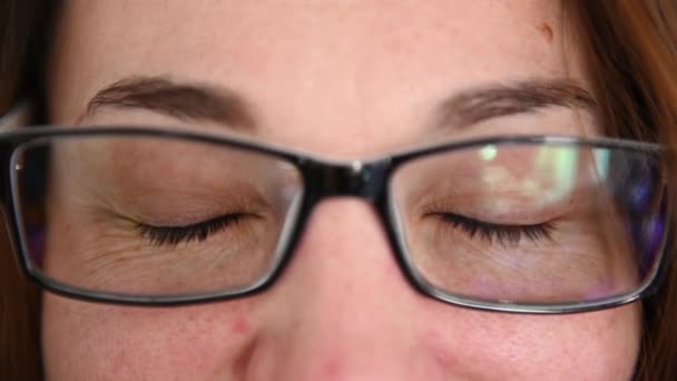 Retrato de mujer en gafas mirando a la cámara y sonriendo alegremente. De cerca. — Vídeos de Stock