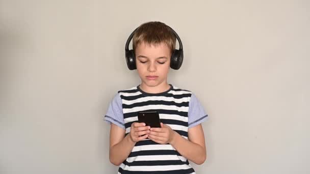 스마트폰으로 헤드폰을 끼고 음악을 듣는 십 대 소년의 문자 메시지 — 비디오