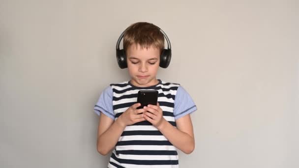 Teenage boy texting using smartphone listening to music wearing headphones — Stock Video