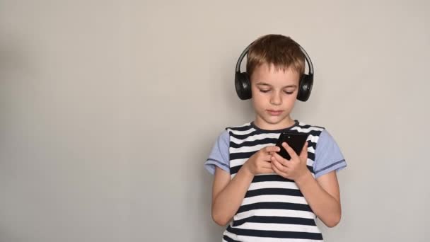 Teenage boy texting using smartphone listening to music wearing headphones — Stock Video