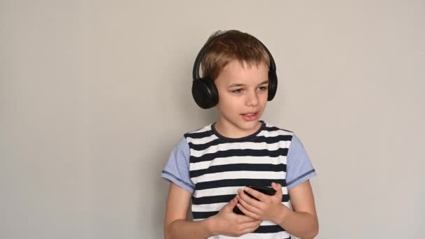 Підлітковий хлопець смс за допомогою смартфона, що слухає музику в навушниках — стокове відео