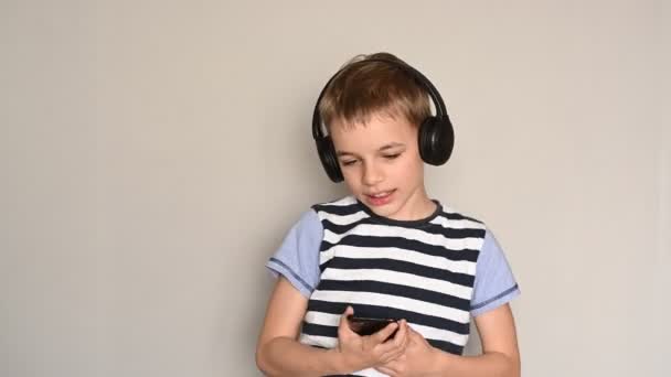 Έφηβος αγόρι γραπτών μηνυμάτων χρησιμοποιώντας smartphone ακούγοντας μουσική φορώντας ακουστικά — Αρχείο Βίντεο