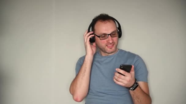 Homem feliz usando telefone celular enquanto ouve música em fones de ouvido — Vídeo de Stock