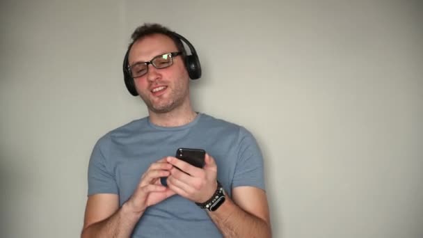 Счастливый человек пользуется мобильным телефоном, слушая музыку в наушниках — стоковое видео