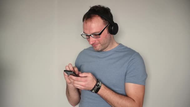Ευτυχής άνθρωπος που χρησιμοποιεί το κινητό τηλέφωνο ακούγοντας μουσική στα ακουστικά — Αρχείο Βίντεο