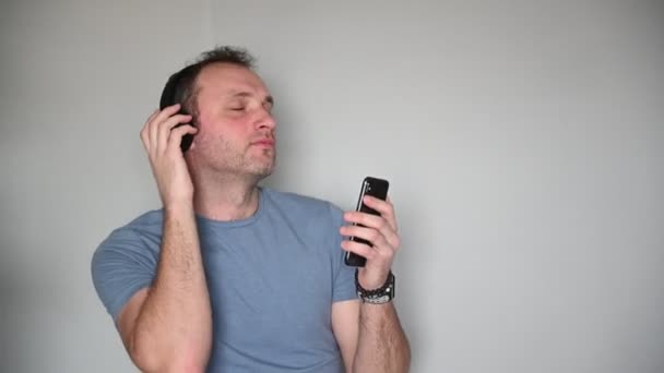 Homme heureux utilisant un téléphone portable tout en écoutant de la musique sur écouteurs — Video