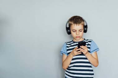 Akıllı telefon kullanarak mesajlaşan, müzik dinleyen, kulaklık takan bir çocuk.