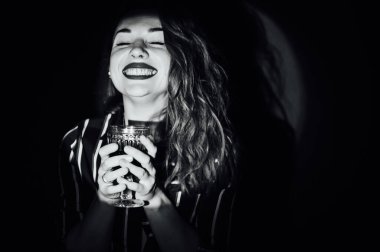 Yeşil arka plandaki kız bir bardak kırmızı içecekle şarap dumanı yana bakıyor.