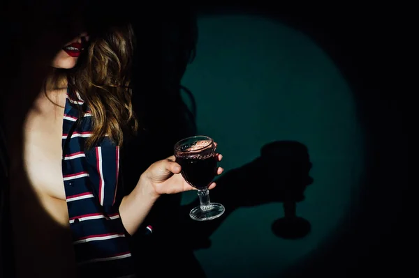 Ragazza su sfondo verde con un bicchiere di vino bevanda rossa fumo guarda da parte — Foto Stock