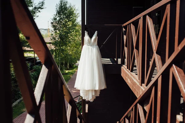 外の木製の手すりにぶら下がってエレガントなウェディングドレス — ストック写真
