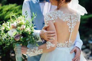 Neşeli yeni evliler düğünlerinde sarılıyorlar ve yüzlerini bir düğün buketi ile kaplıyorlar.