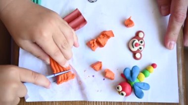 Küçük bir çocuk plastikçilik oynuyor. Çeşitli küçük heykeller yapıyor..