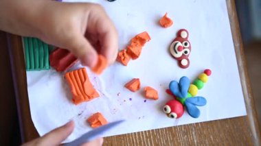 Küçük bir çocuk plastikçilik oynuyor. Çeşitli küçük heykeller yapıyor..