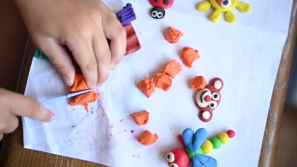 Um rapazinho joga plasticina. Ele faz várias pequenas esculturas . — Vídeo de Stock