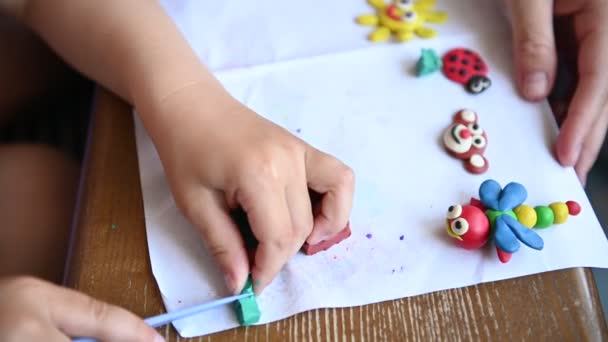 Un ragazzino gioca alla plastilina. Mamma lo aiuta a volte. — Video Stock