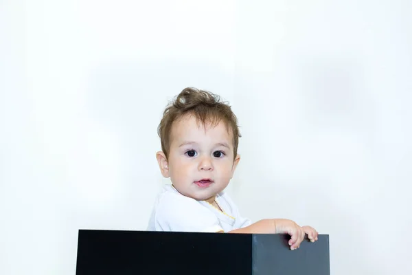 Um jovem menino espreitando de uma caixa em um fundo branco — Fotografia de Stock