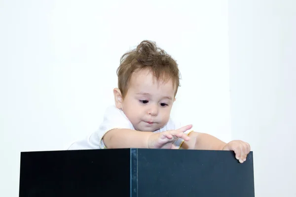 Egy fiatal csecsemő fiú less egy dobozból egy fehér háttér — Stock Fotó