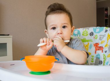 Bir kaşık yulaf ezmesi kahvaltı olarak sahip yürümeye başlayan çocuk karışıklık ve başlarken kirli bebek yemek yeme bebek