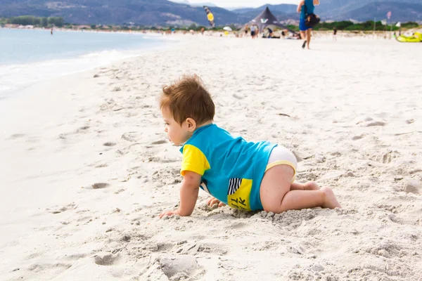 Niño pequeño con traje protector azul impetuoso jugando en la playa tropical del océano. Protección UV y solar para niños pequeños. Niño pequeño durante las vacaciones familiares en el mar. Verano diversión agua . —  Fotos de Stock