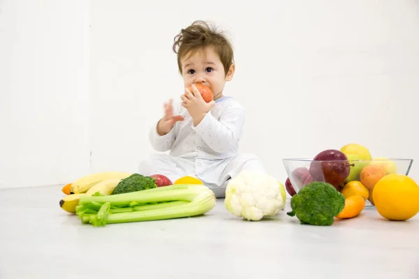 Το μωρό σε ένα περιβάλλον από φρέσκα λαχανικά, απομονωμένο στο λευκό — Φωτογραφία Αρχείου
