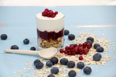 Tahıllı yoğurt ve eski ahşap arka planda cam kasede taze yaban mersini. Eski efekt.